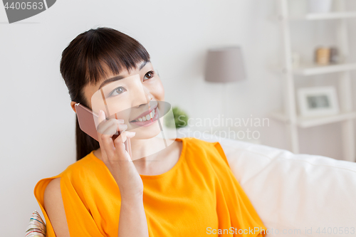 Image of happy asian woman calling on smartphone at home