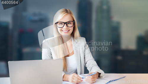 Image of businesswoman with notepad and laptop at office