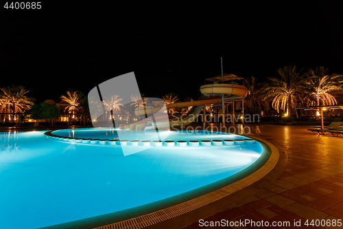 Image of illuminated pool at night with tropical palms
