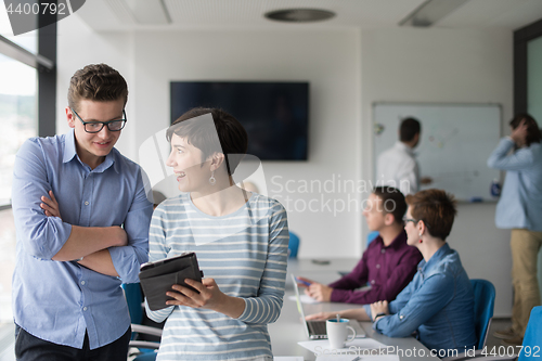 Image of Two Business People Working With Tablet in office