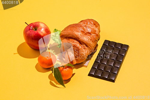 Image of The apple, chocolate and croissants on yellow background