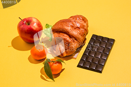 Image of The apple, chocolate and croissants on yellow background