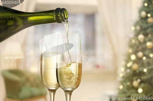 Image of Glasses with champagne and bottle over sparkling holiday background