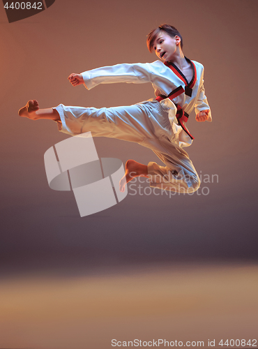 Image of Young boy training karate on blue background