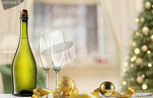 Image of Glasses with champagne and bottle over sparkling holiday background