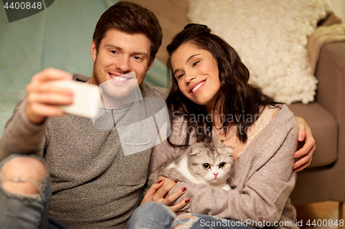Image of happy couple taking selfie by smartphone at home