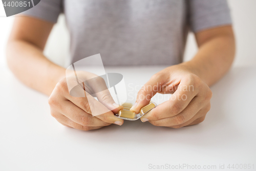 Image of woman hands opening pack of medicine capsules