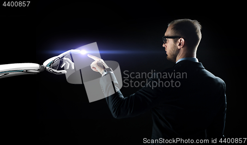 Image of robot and human hand flash light over black