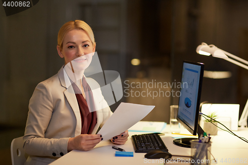 Image of businesswoman with papers working at night office