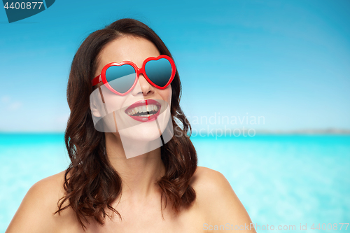 Image of woman with heart shaped shades over sea and sky
