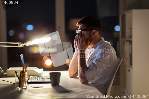 Image of tired businessman with laptop at night office