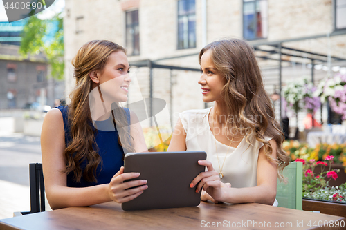 Image of happy young women with tablet pc at outdoor cafe