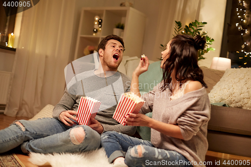 Image of happy couple eating popcorn at home