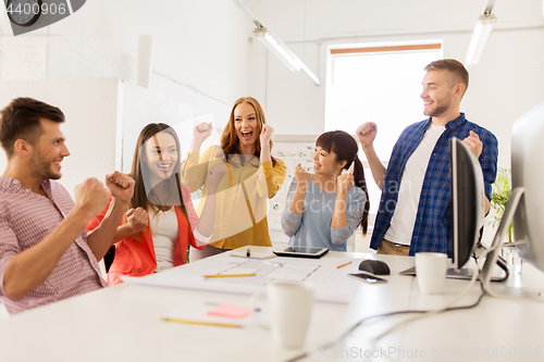 Image of happy creative team celebrating success at office