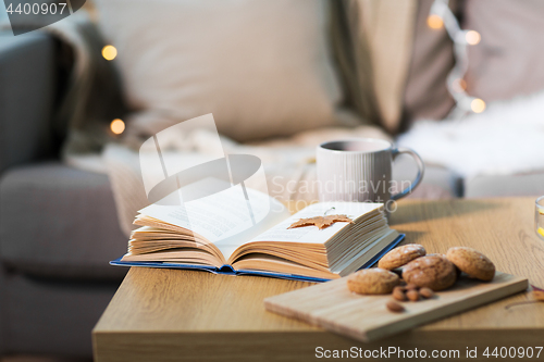 Image of book with autumn leaf, cookies and tea on table