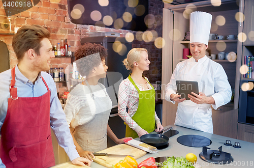 Image of happy friends with tablet pc in kitchen