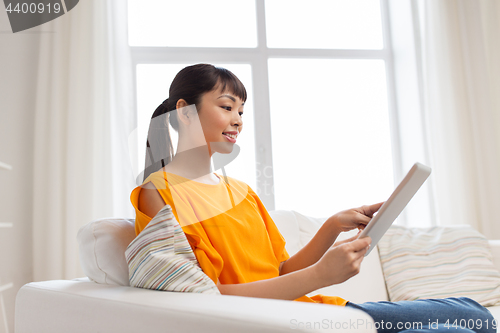 Image of happy young asian woman with tablet pc at home