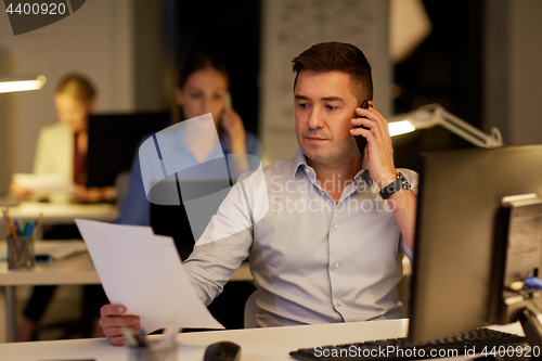 Image of businessman calling on sartphone at night office