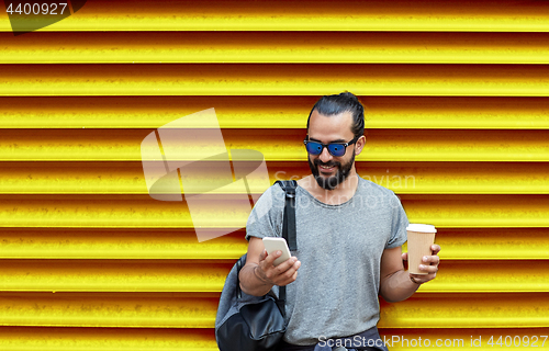 Image of man with coffee cup and smartphone over wall