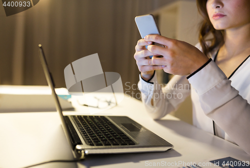 Image of businesswoman with smartphone and laptop at office