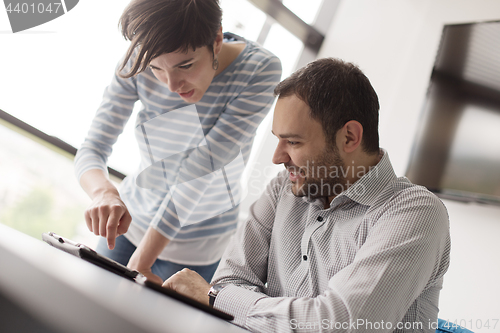 Image of Two Business People Working With Tablet in startup office