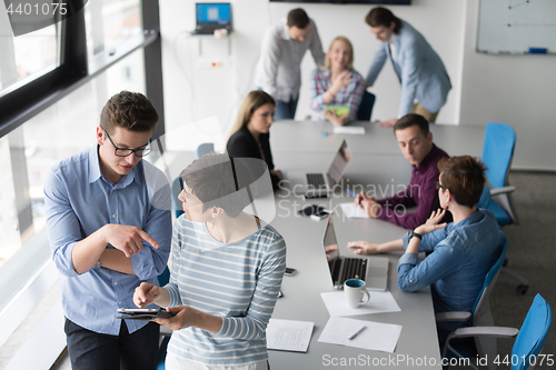 Image of Two Business People Working With Tablet in office