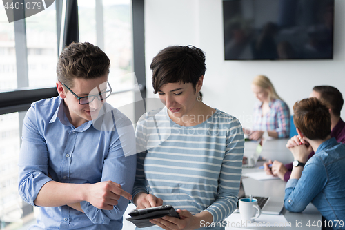 Image of Two Business People Working With Tablet in office