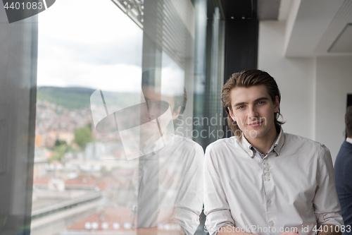 Image of young businessman in startup office by the window