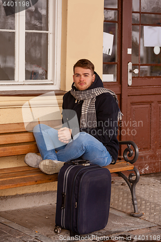 Image of Young man sitting in winter on a bench