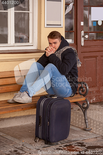 Image of Young man sitting in winter on a bench