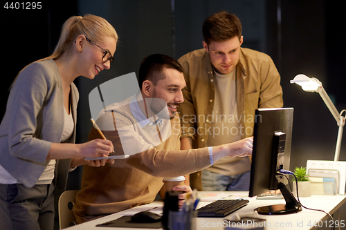 Image of business team with computer working late at office