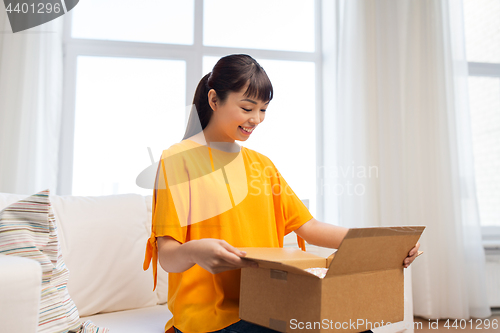 Image of happy asian young woman with parcel box at home