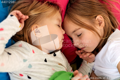 Image of happy little girls sleeping in bed at home