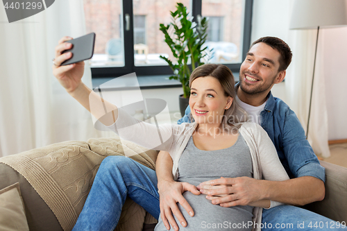 Image of man and pregnant woman taking selfie at home