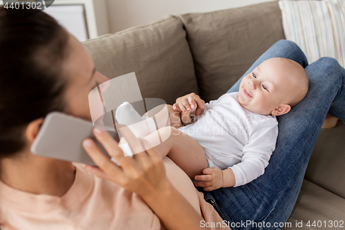 Image of mother with baby calling on smartphone at home