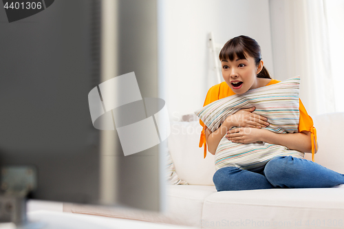 Image of stunned asian woman with watching tv at home