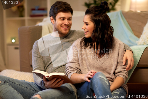 Image of happy couple reading book at home