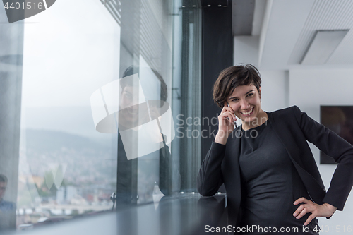 Image of Elegant Woman Using Mobile Phone by window in office building