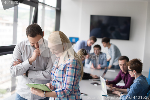 Image of Two Business People Working With Tablet in office