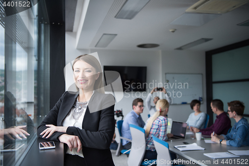 Image of Elegant Woman Using Mobile Phone by window in office building