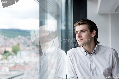 Image of young businessman in startup office by the window