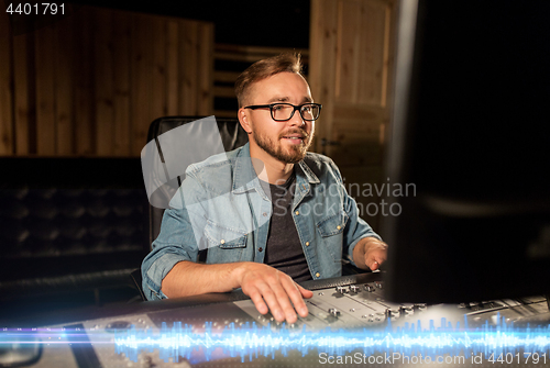 Image of man at mixing console in music recording studio