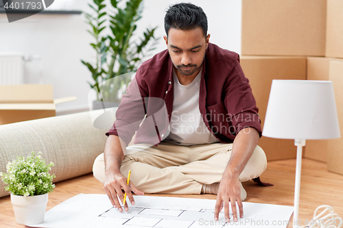 Image of man with blueprint and boxes moving to new home