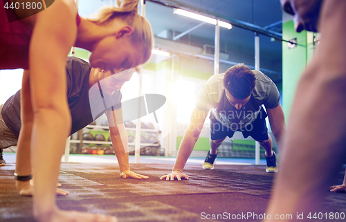 Image of group of people doing straight arm plank in gym