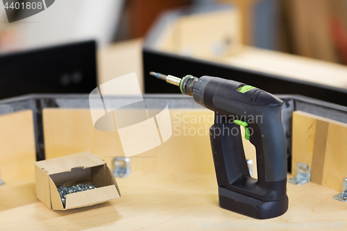 Image of screwdriver with screws and furniture at workshop