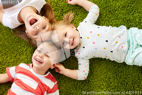 Image of happy little kids lying on floor or carpet