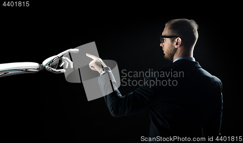 Image of robot and human hand flash light over black