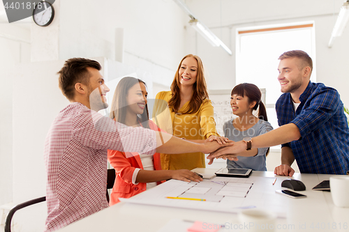 Image of creative team holding hands together at office