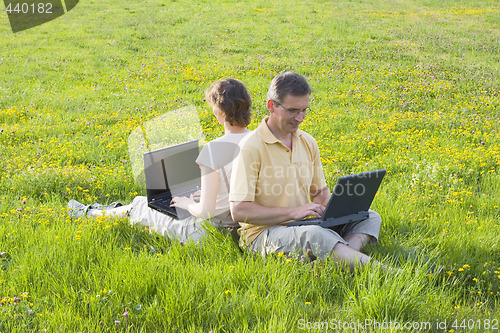 Image of Coupe sitting with laptops in a meadow