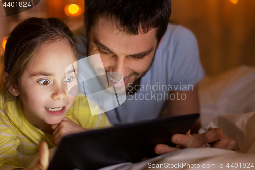 Image of family with tablet pc in bed at night at home